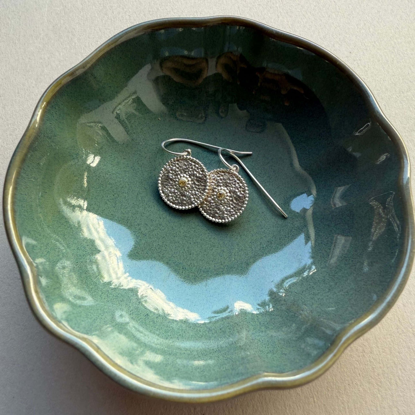 Ohrringe aus Fairmined Silber mit fair gehandelten gelben Saphiren, präsentiert in einer kleinen Keramikschale