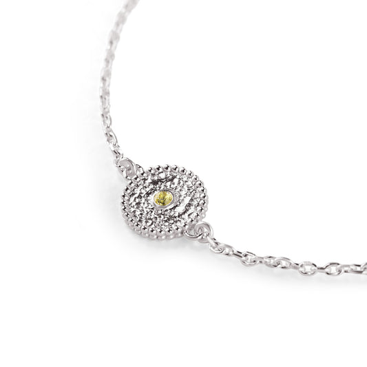 Nahaufnahme eines zierlichen Charms aus Fairmined Silber, am Rand mit kleinen Kügelchen verziert, mittig ein hellgelber fair gehandelter Saphir, freigestellt auf weißem Hintergrund