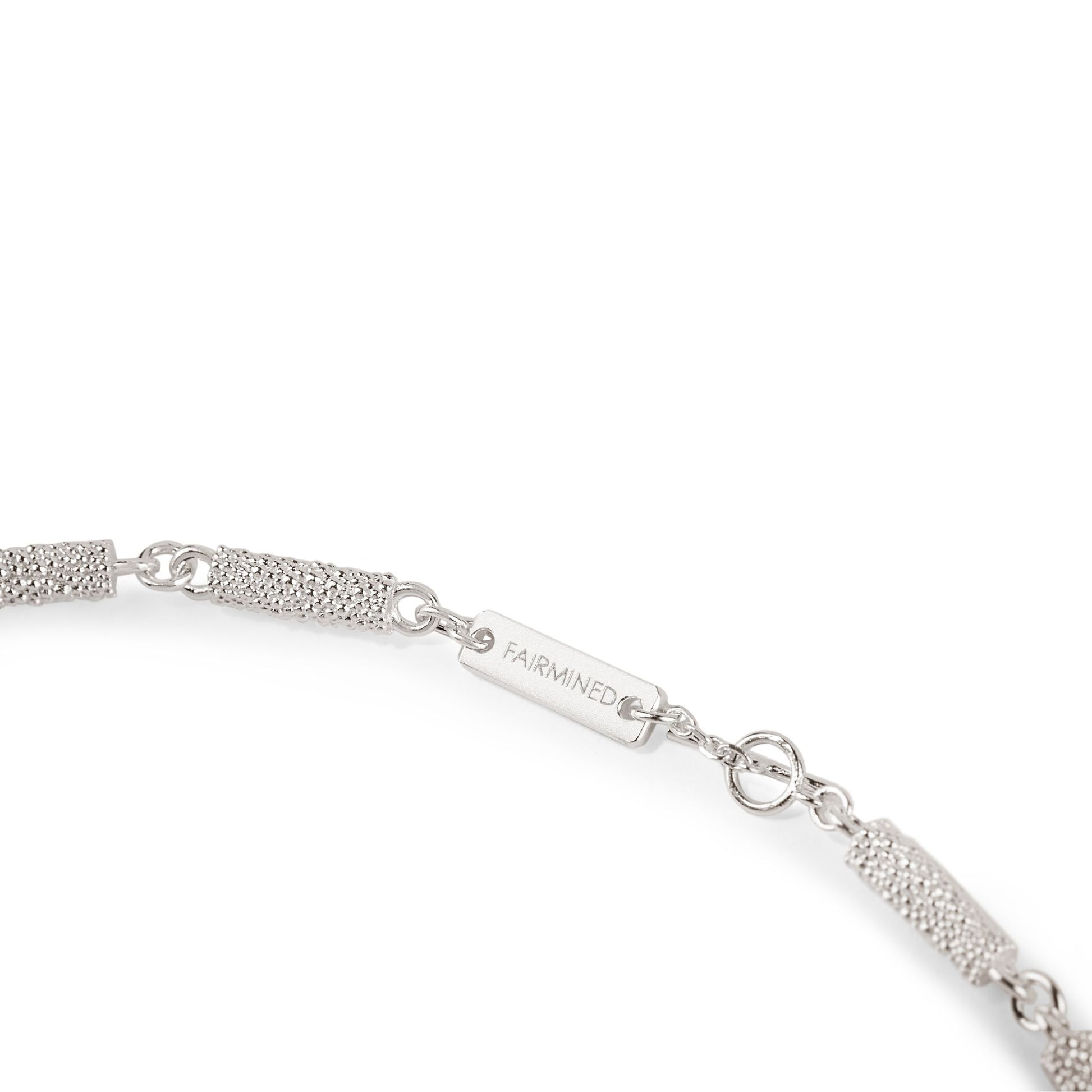 Nahaufnahme des Verschlusses einer Halskette aus Fairmined Silber mit Gravur „Fairmined“, freigestellt auf weißem Hintergrund