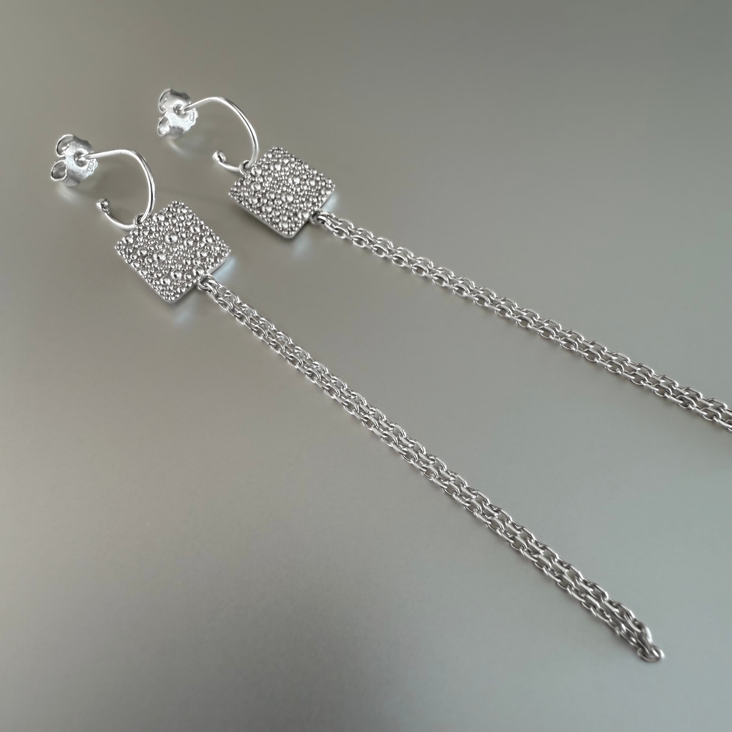 Mini Creolen mit langen Anhängern aus Fairmined Silber, liegend fotografiert – natürliche Produktaufnahme