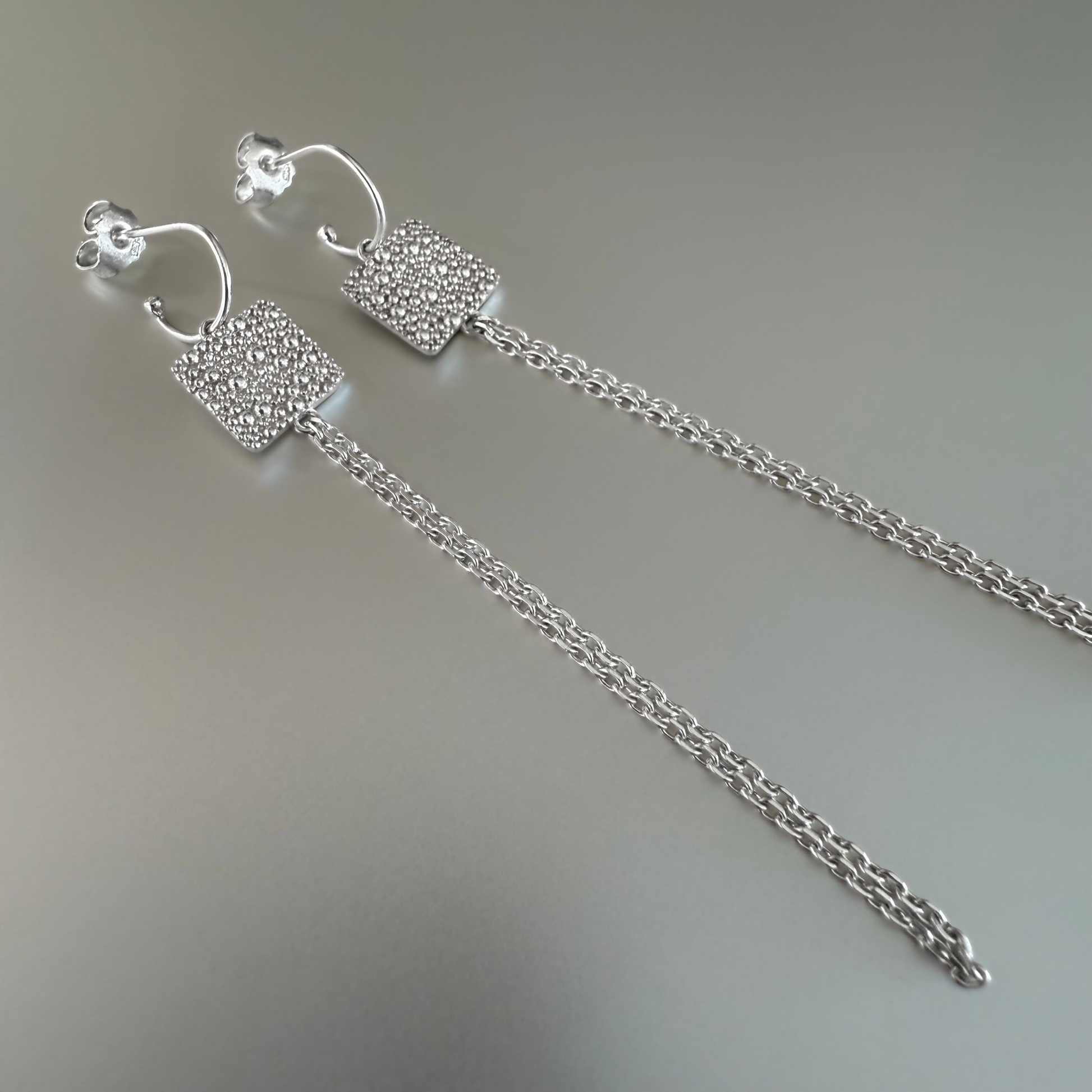 Mini Creolen mit langen Anhängern aus Fairmined Silber, liegend fotografiert – natürliche Produktaufnahme