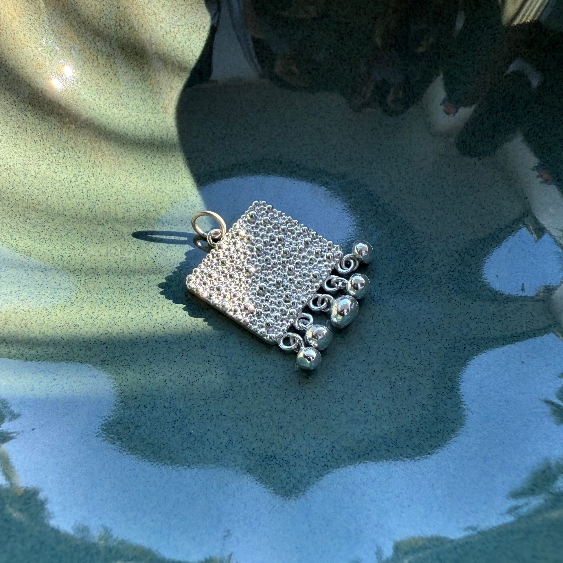 Nahaufnahme von Fairmined Silber Anhänger mit strukturierter Oberfläche und Kügelchen, in kleiner Keramikschale