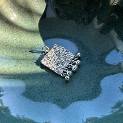 Nahaufnahme von Fairmined Silber Anhänger mit strukturierter Oberfläche und Kügelchen, in kleiner Keramikschale