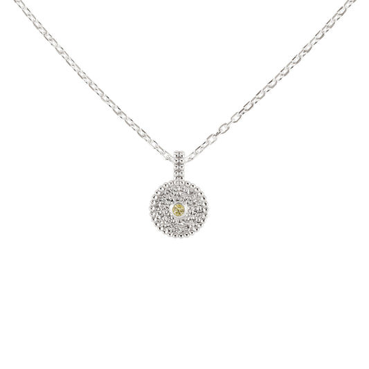 Nahaufnahme eines runden Anhängers aus Fairmined Silber mit hellgelbem, fair gehandeltem Saphir, strukturierter Oberfläche und Kügelchenrand, hängend an Kette, freigestellt